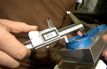 A vector illustration shows a worker with a clipboard using a digital floor scale to weigh a pallet containing boxes.